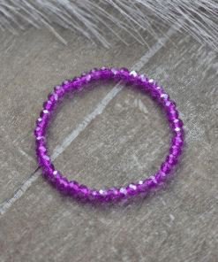 De kralenarmband is geregen op elastiek met paarse facet kralen