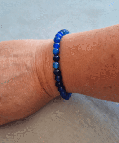 De blauwe glaskralenarmband oceaanblauw gedragen om een pols